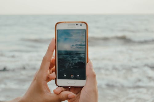 Orang Yang Memegang Smartphone Menangkap Gelombang Laut