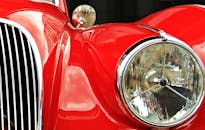 特写镜头展示了一辆老式红色汽车，其闪亮的镀铬细节和独特的前灯清晰可见