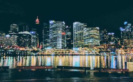 Stunning night view of Sydney's CBD skyline reflecting on the harbor waters, vibrant city lights.