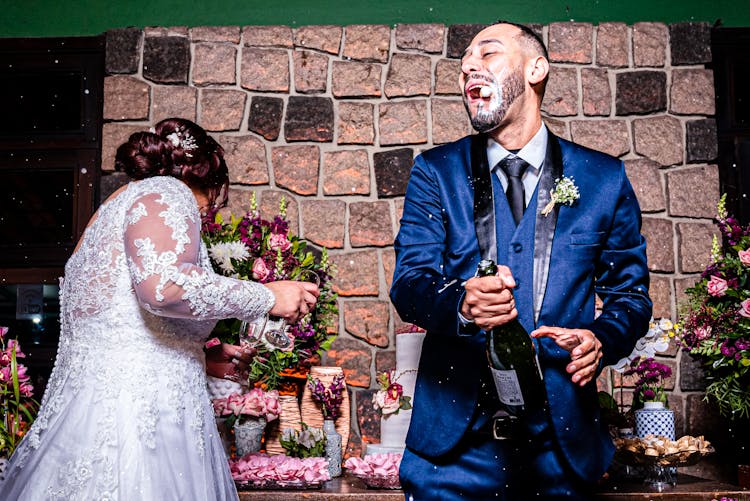 Happy Bridegroom Opening A Bottle Of Champagne