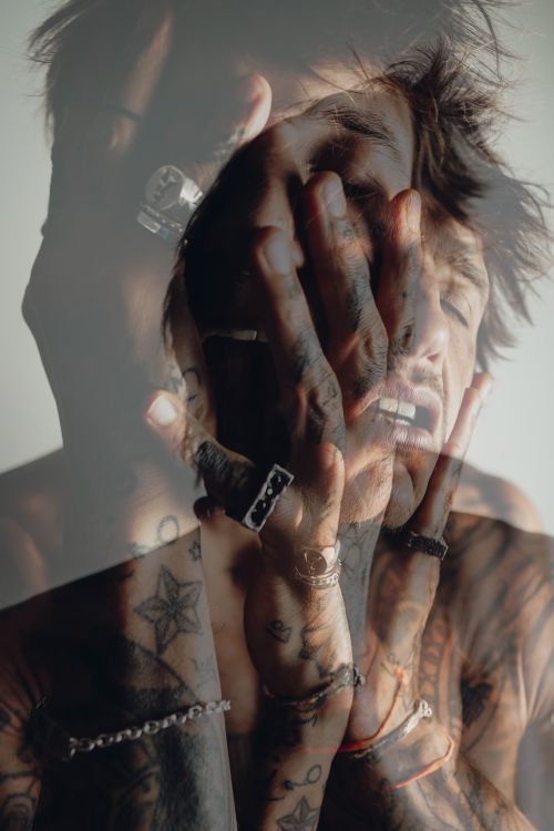 Free Moody double exposure portrait of a man with tattoos and jewelry in an emotional pose. Stock Photo