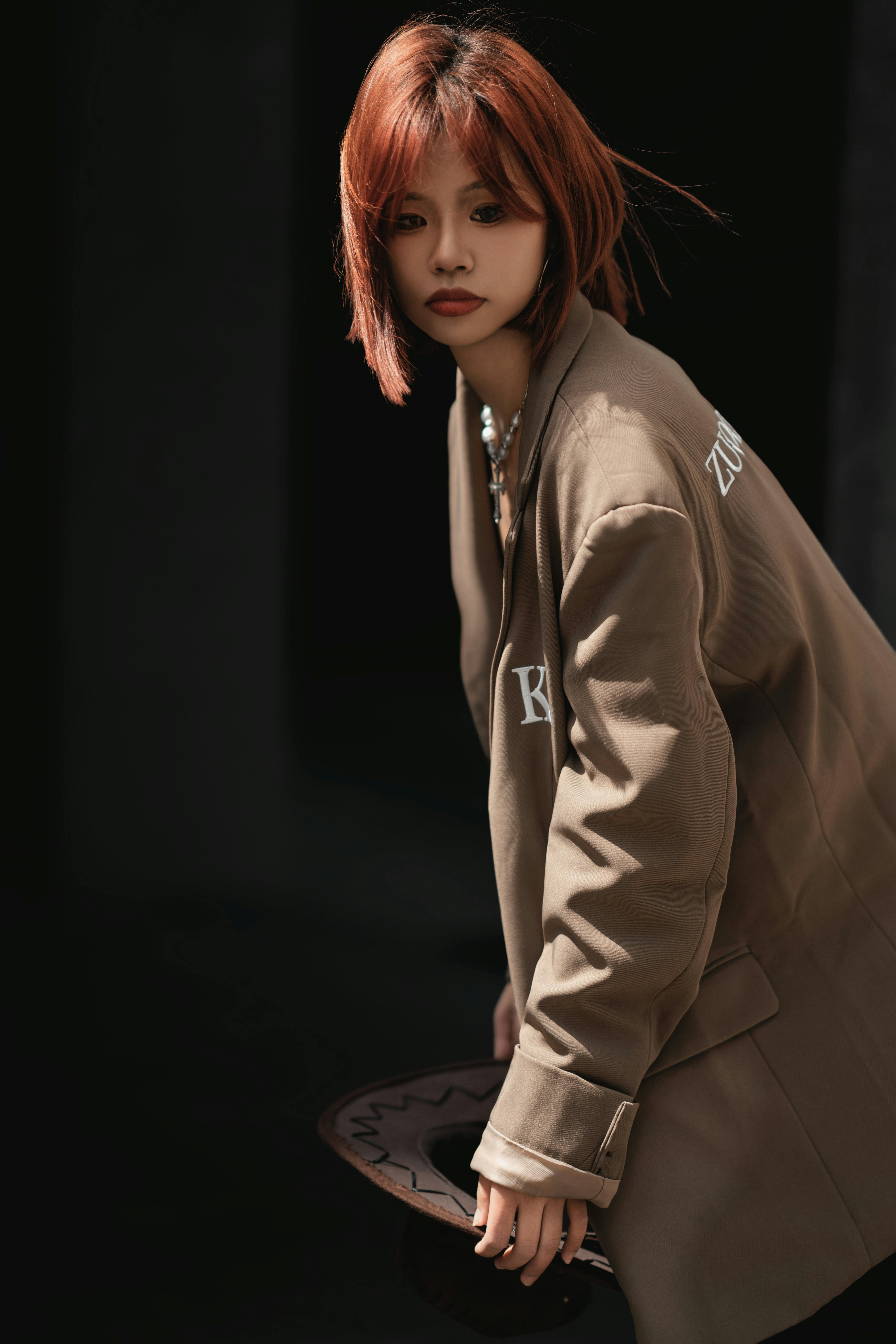 Fashionable woman with brown hair poses outdoors in an oversized jacket.