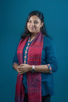 Portrait of a young woman smiling, wearing traditional attire with a blue background.