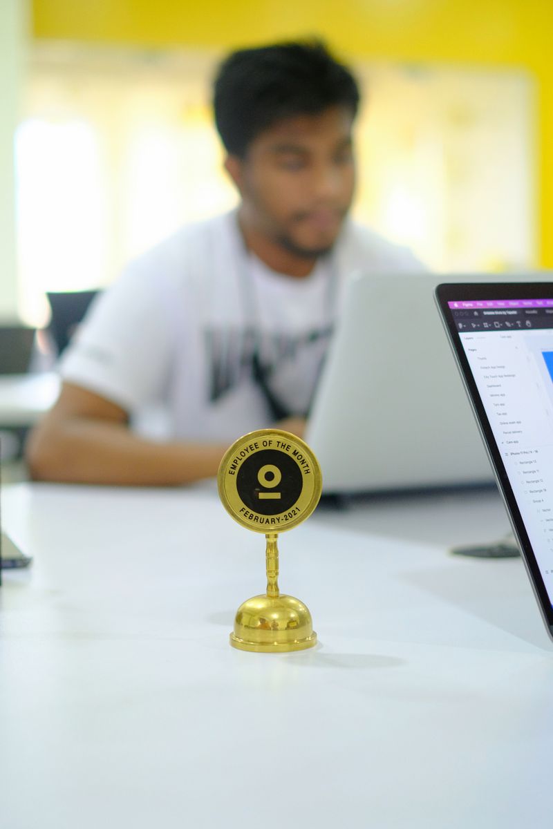 Blurred background office setup featuring an Employee of the Month trophy with a focus on modern work culture.