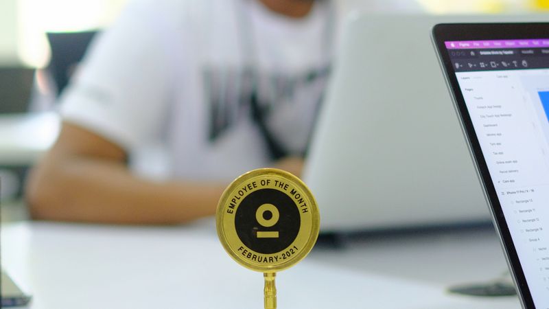 Blurred background office setup featuring an Employee of the Month trophy with a focus on modern work culture.