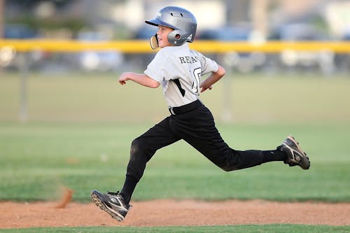 бесплатная бейсболист в серо черной форме бежит Стоковое фото