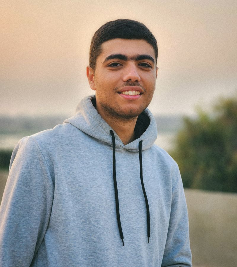 Fotografía de referencia de un hombre sonriente al aire libre con hoodie gris y el logotipo TimeParche superpuesto como mockup