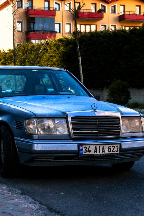 Free A classic Mercedes-Benz car parked on a street with an urban backdrop. Stock Photo
