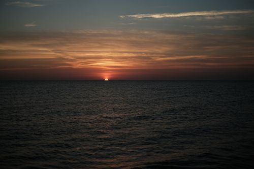 Free A tranquil sunset over the ocean with colorful sky and calm waters. Stock Photo