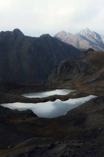 A breathtaking view of a mountain lake surrounded by rugged peaks under a cloudy sky.