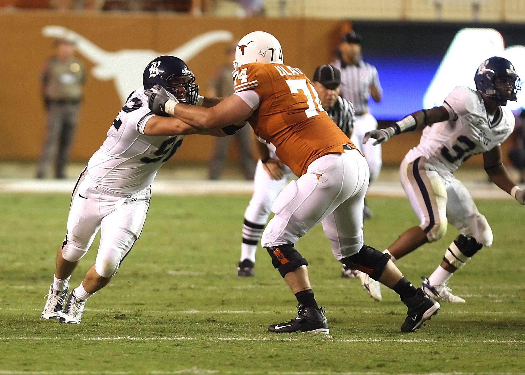 Athletes in action during an American football game on a grassy field.