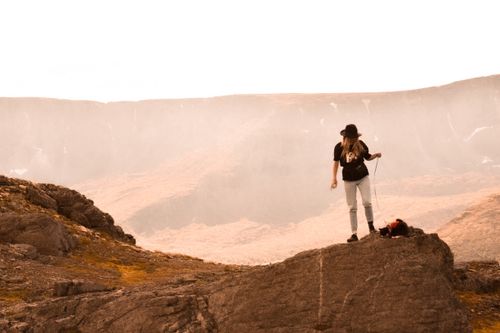 Free Woman with a dog on a leash hiking a rocky mountain during the day. Stock Photo
