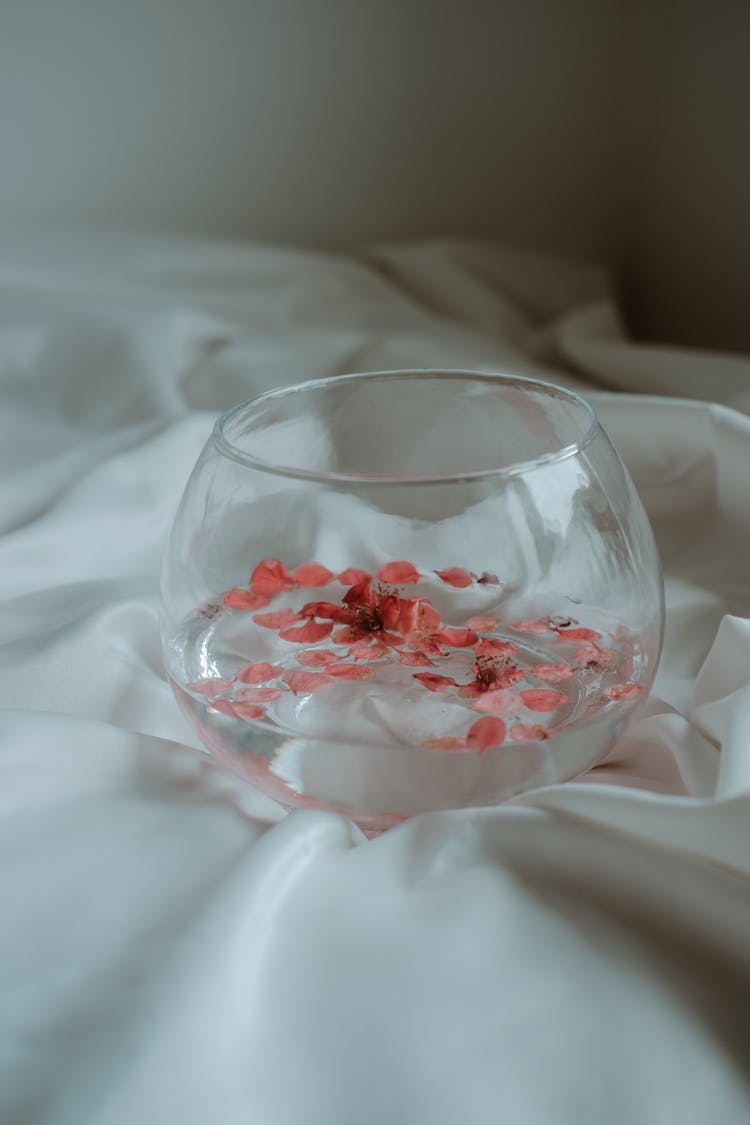 A Glass Of Water With Pink Flower Petals 