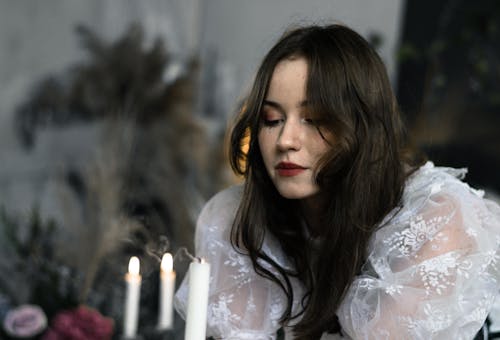 Young Woman in a Lace Dress Blowing Out a Candle