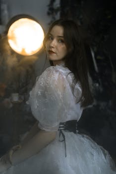 Romantic portrait of a woman in a white gown surrounded by soft glowing light.