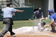 在棒球比赛的一个激动人心时刻，球员在接球手的压力下滑向本垒板