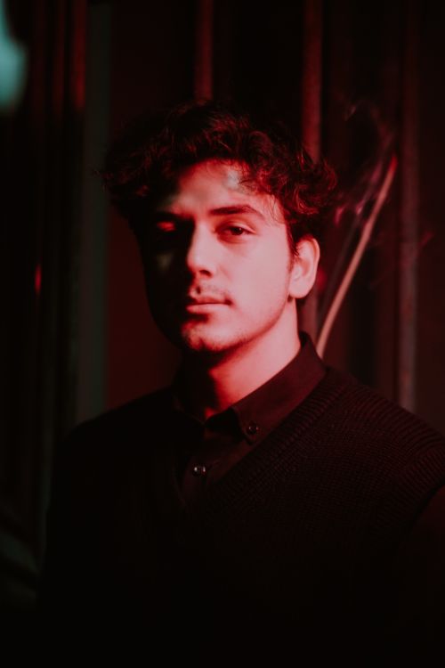 Free Moody portrait of a young man under red lighting creating dramatic shadows. Stock Photo