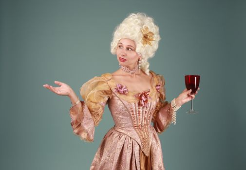 Woman in a Rococo-style dress holding a glass of red wine against a gray background.