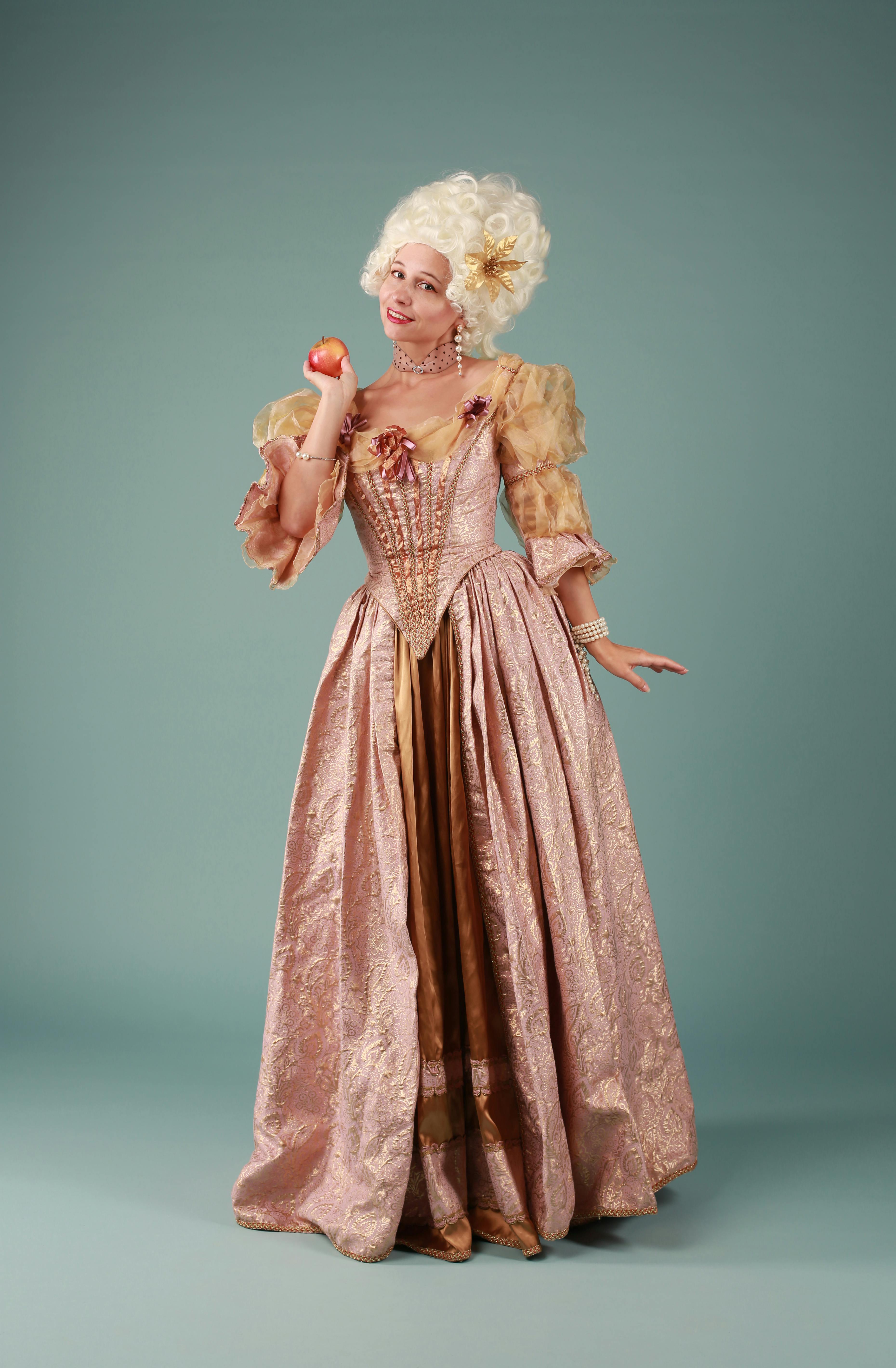 A woman in a Rococo-style gown holding an apple, embodying elegance and historical fashion.