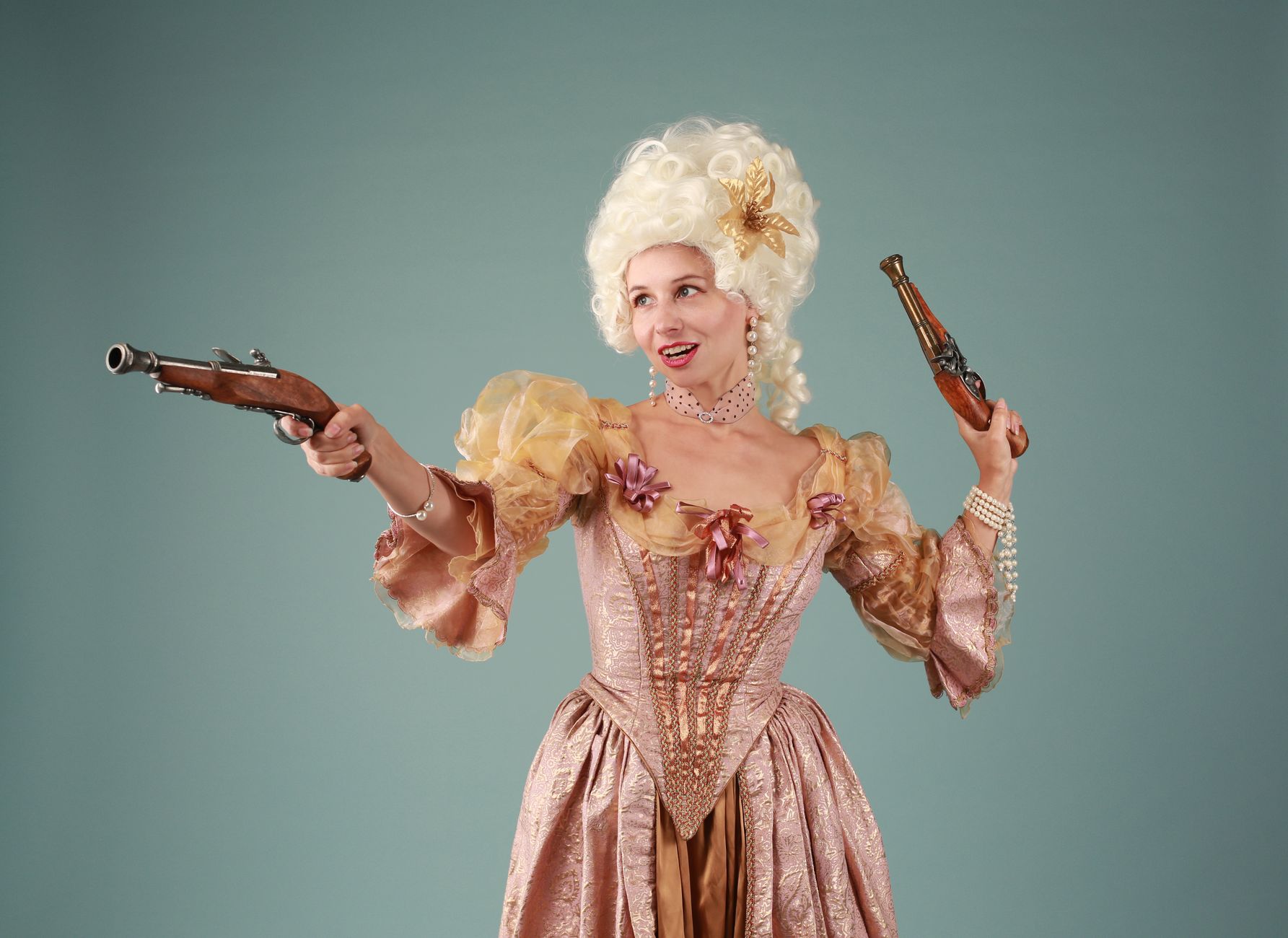 A young woman in baroque costume poses holding flintlock pistols, exuding elegance and historical charm.