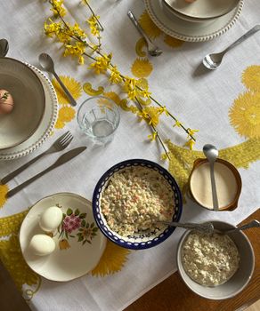 A top view of a festive Easter table setting with salads, eggs, and yellow floral accents.