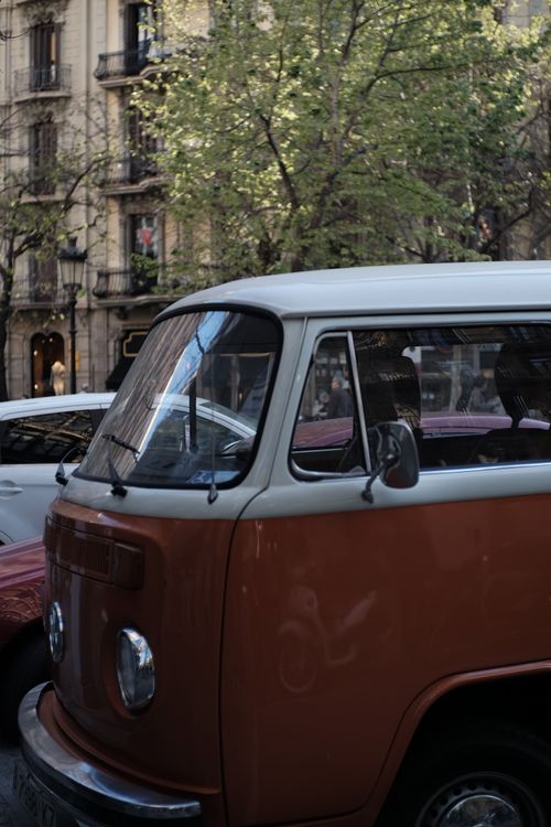 Free Classic red van parked on a tree-lined street in Barcelona's urban center. Stock Photo