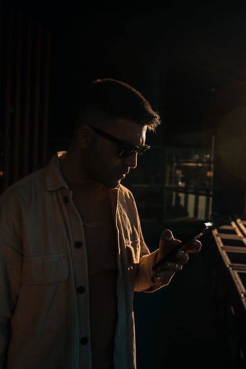 Man in Sunglasses Standing with Smarrtphone in Shadow