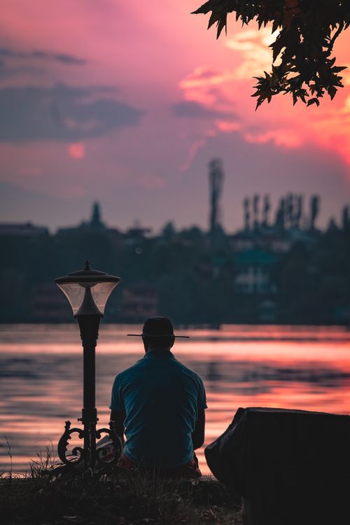 Free A man enjoys the serene sunset over the water in Srinagar, featuring vibrant colors and peaceful ambiance. Stock Photo