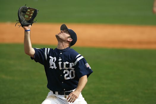 Baseball player in blue jersey catching a ball on a grassy field during a game.