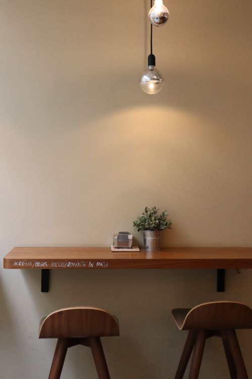 Free Warm café interior with wooden chairs, a potted plant, and hanging light bulbs in Ferrol, Spain. Stock Photo