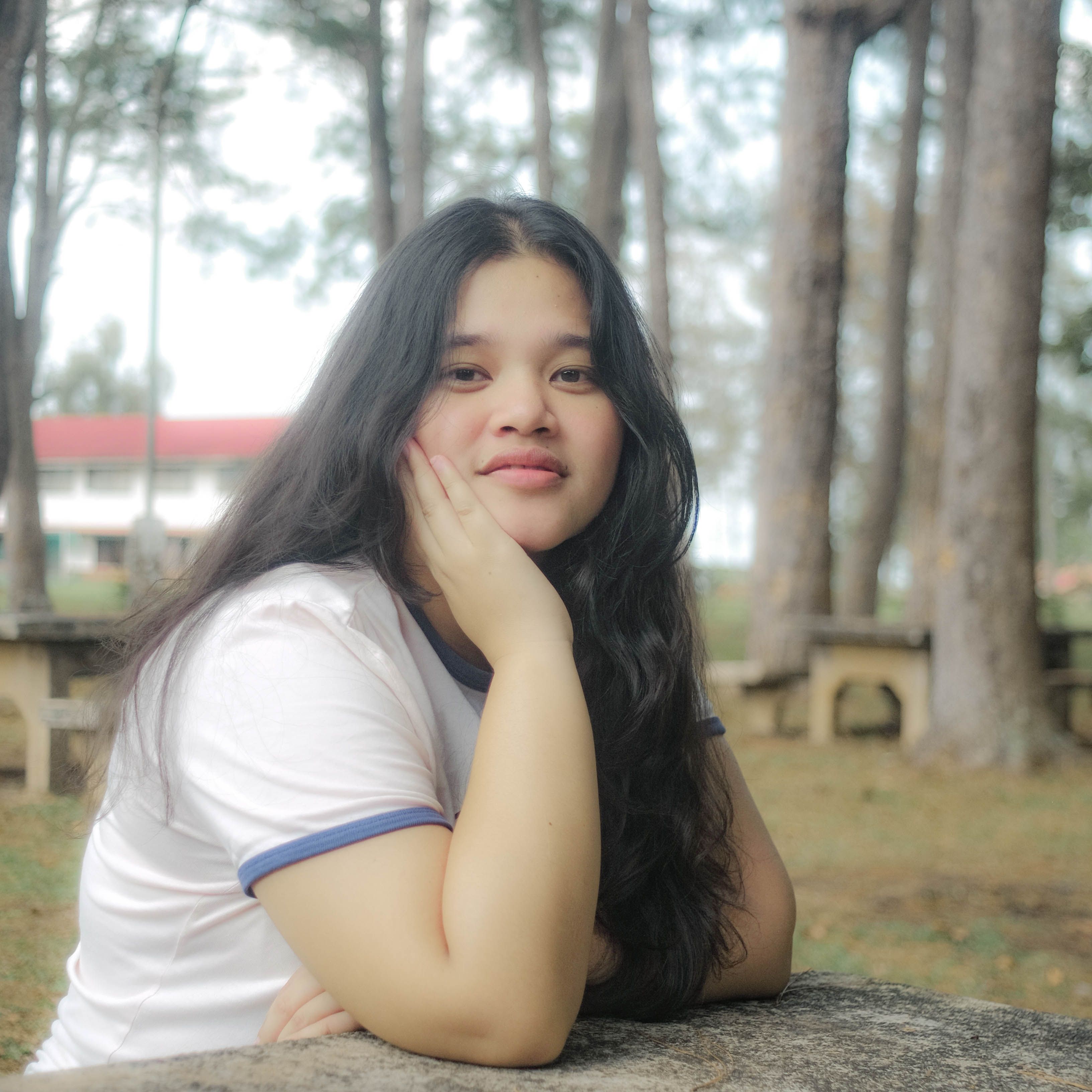 Portrait of a young woman relaxing at a forest picnic table, enjoying leisure time outdoors.