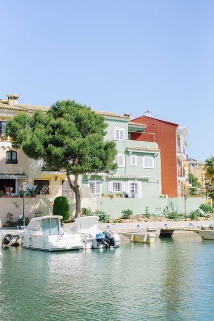 Vibrant colorful houses by a marina with boats, under a clear blue sky. Ideal vacation spot.