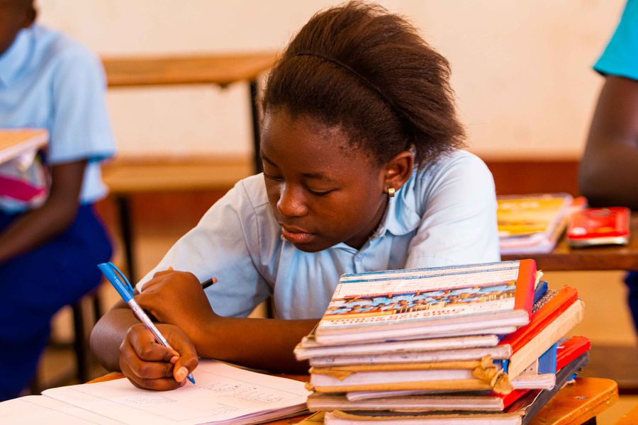 A schoolgirl in uniform writing in a notebook