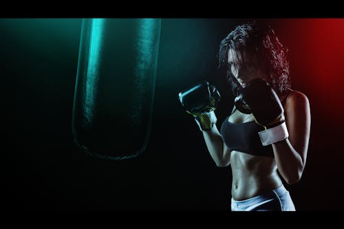 Mulher Em Luvas De Boxe Com Sutiã Esportivo Posando Em Estilo De Boxe Na Frente Do Saco De Pancadas