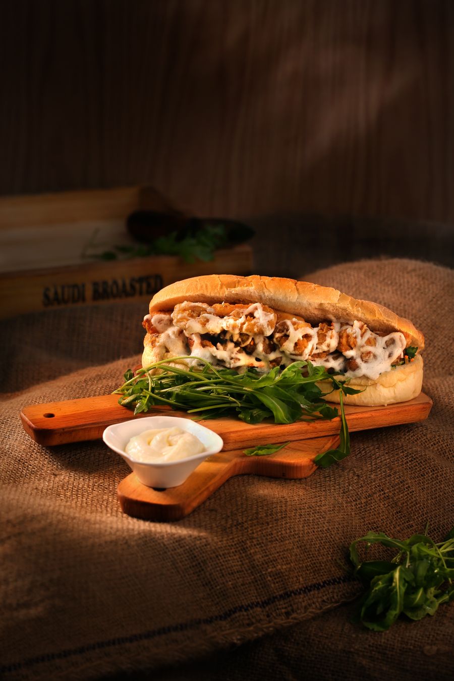 A loaded sub with chopped meat and white sauce on a long roll