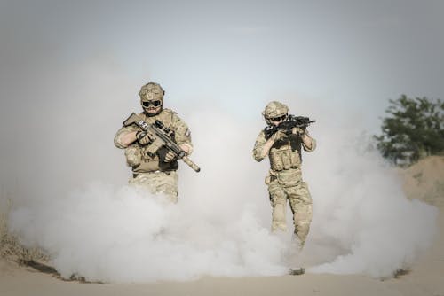 Free Men Holding Rifle While Walking Through Smoke Grenade Stock Photo