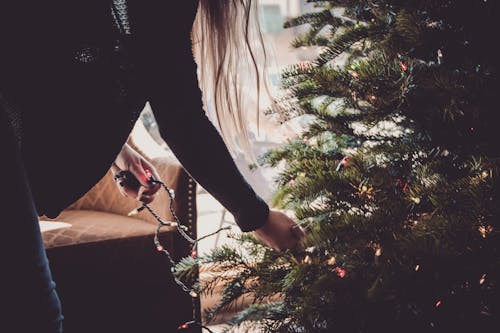 Woman Putting String Lights on Christmas Tree