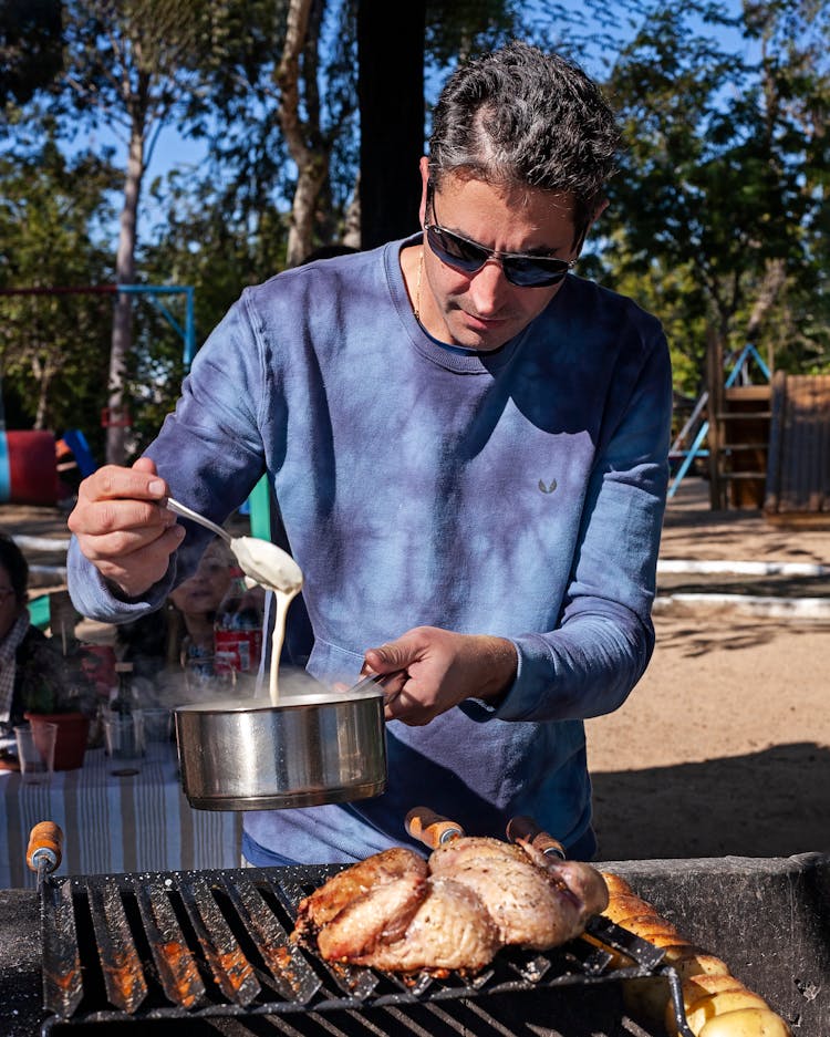 Man Holding Pot Over Barbecue