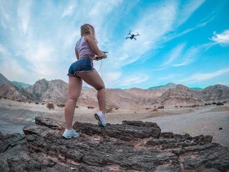 A blonde woman controls a drone amidst the stunning rock formations of Ras al Khaimah, UAE.