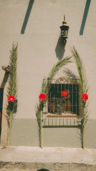 Vibrant red flowers and palm decorations on a traditional house wall in San Miguel de Allende, Mexico.