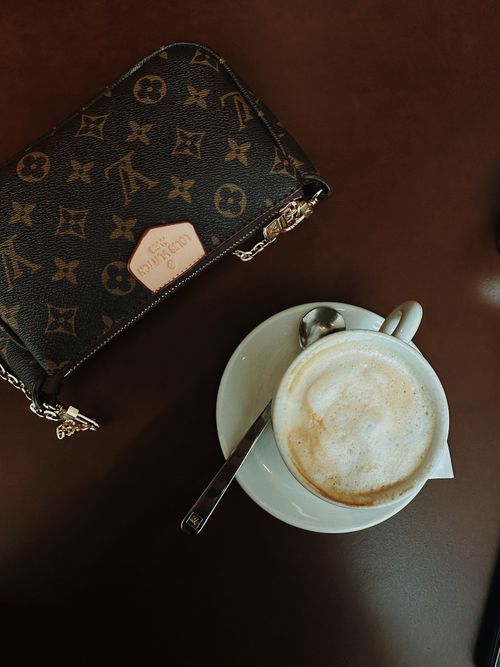 Free Aerial view of a cappuccino and designer handbag in a cozy cafe setting. Stock Photo