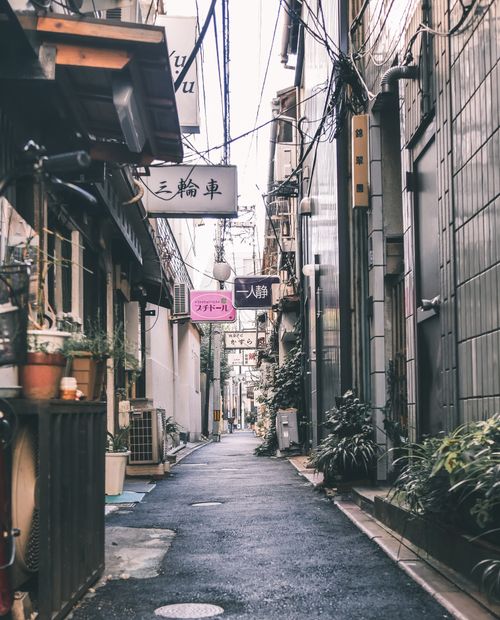 Free Explore a quaint urban alleyway lined with signage and a cozy atmosphere, perfect for tourism. Stock Photo
