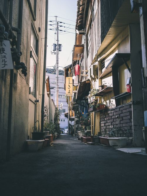 Free Explore a narrow, serene alley lined with rustic buildings and urban charm in daylight. Stock Photo