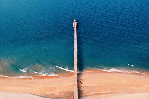 Free A stunning aerial shot of the jetty at Kijal Beach, Malaysia, leading into blue ocean waters. Stock Photo