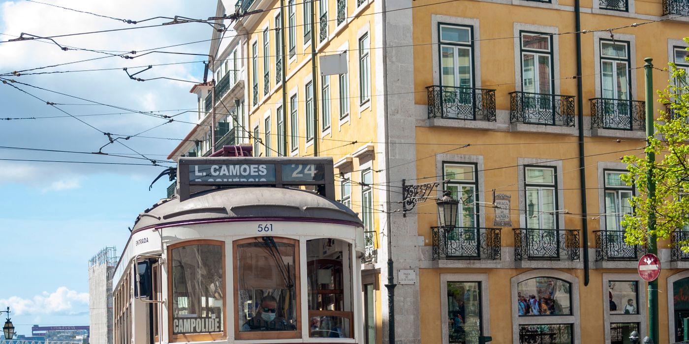 A yellow Tram 28 on a narrow Lisbon street