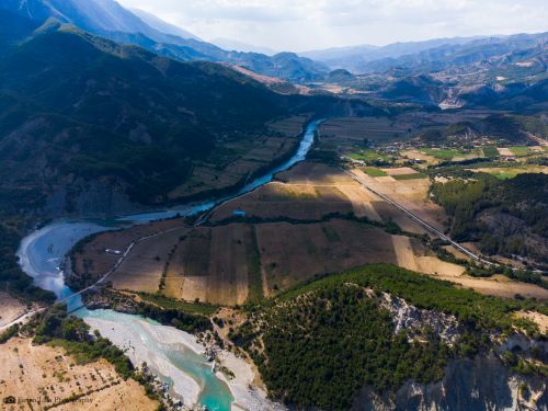 Free Stunning aerial view of a picturesque river valley with fields and mountains. Stock Photo