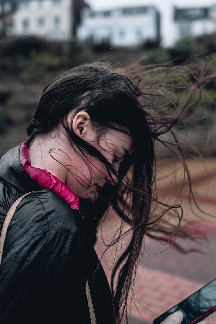 Young Woman With Messy Hair Walking Outdoors In Rain And Wind 