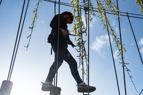 Free A man wearing safety gear enjoys a high ropes course on a sunny day in Scarborough, UK. Stock Photo