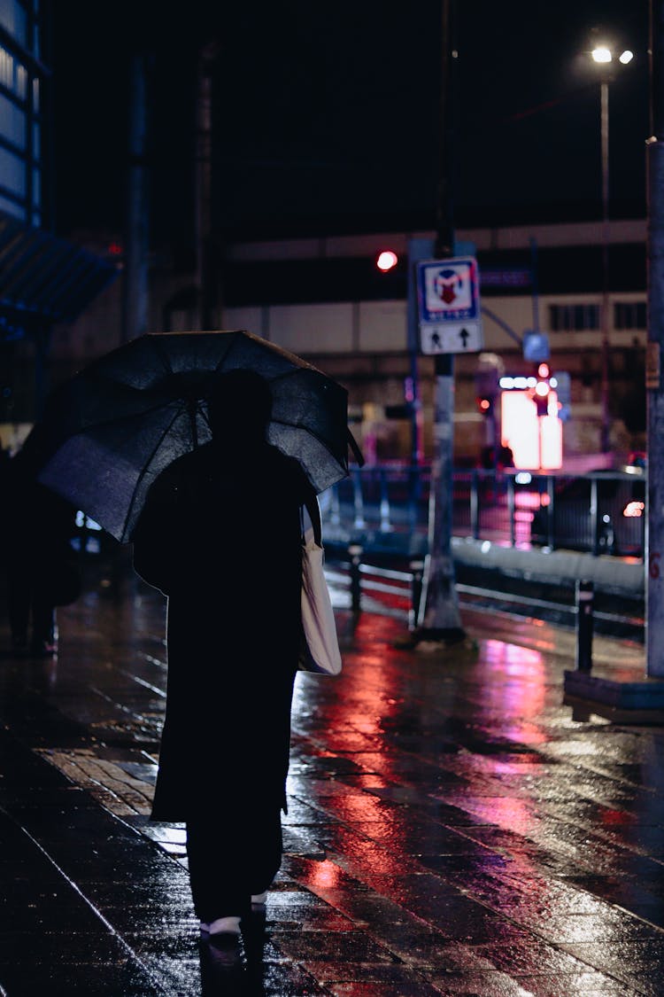 Woman Walking With An Umbrella On A Wet Sidewalk