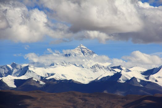 Beautiful snow-covered mountain peaks under fluffy clouds, showcasing nature's grandeur.